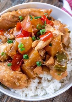 a white bowl filled with rice and chicken on top of a wooden table next to a fork