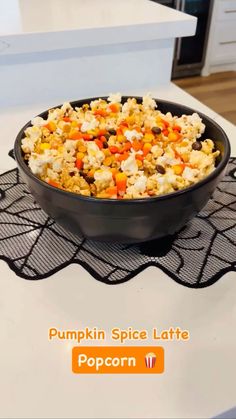 a black bowl filled with popcorn sitting on top of a white kitchen counter next to an oven