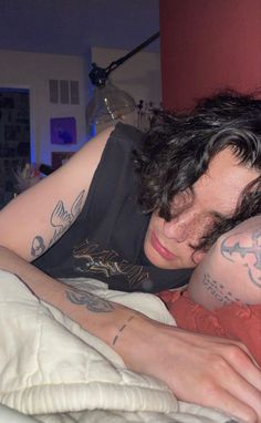 a man laying in bed with tattoos on his arm