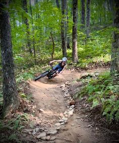 a man riding on the back of a bike down a dirt trail in the woods