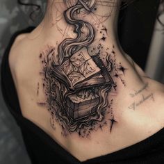 a woman's neck with a book and compass tattoo on the back of her neck