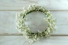 a white wreath with baby's breath flowers on a wooden surface, ready to be used as a wedding decoration