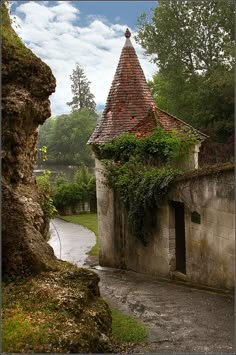 an old stone building with ivy growing on it's roof and door, next to a river