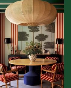 a dining room with red and white striped wallpaper, blue chairs and a round table