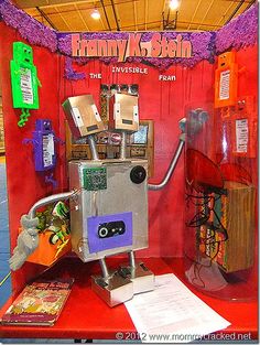 the robot is on display in front of a red wall with purple and green decorations