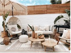 an outdoor living room with wicker furniture and plants on the floor, along with white brick walls