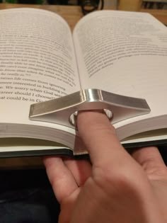 a person is holding a book with a ring on it and pointing to the page