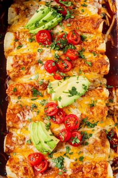 an enchilada dish with tomatoes, avocado and other toppings