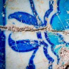 an artistic blue and white tile design on the outside of a building with peeling paint