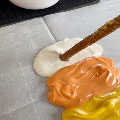 three different colors of icing next to a rolling doughnut on a counter top