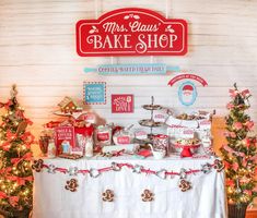 a table topped with lots of desserts next to small christmas trees and other decorations