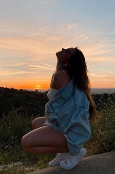 a woman sitting on the ground with her eyes closed and looking up at the sky