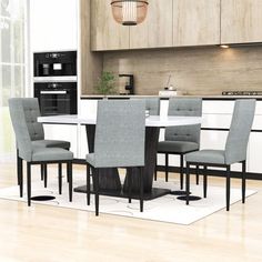 a dining room table and chairs in front of a kitchen with an oven on the wall