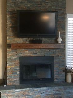 a flat screen tv mounted on top of a stone fireplace