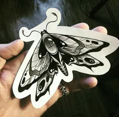 a hand holding a sticker with a black and white butterfly on it's wings