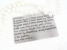 a necklace with a poem written on it and pearls around the neck, sitting on a white surface