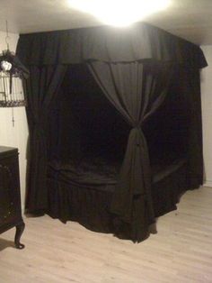 a black canopy bed sitting on top of a hard wood floor next to a dresser