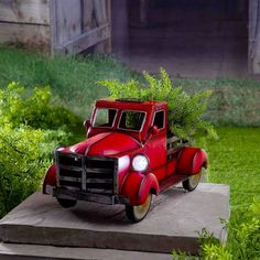 an old red truck with a planter in the back is sitting on some concrete