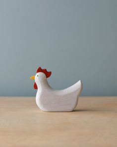 a small white chicken sitting on top of a wooden table