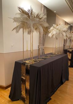 there is a table with black cloths and gold decorations on it, along with two tall palm trees