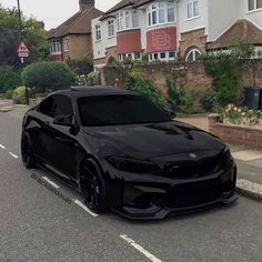 a black car is parked on the side of the road in front of some houses