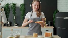 a woman in an apron holding a piece of bread