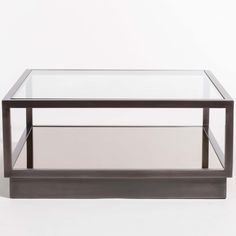 a glass and metal coffee table with two shelves on each side, against a white background