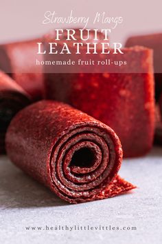 a roll up of fruit leather sitting on top of a white surface with text overlay that reads strawberry mango fruit leather homemade fruit roll - ups