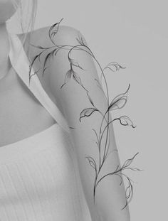 a woman's arm with vines on it and a white shirt in the background