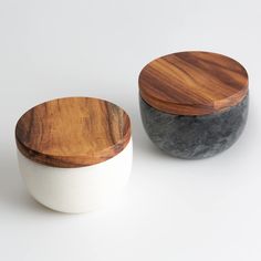 two wooden and white bowls sitting next to each other on top of a white surface