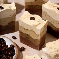 four pieces of cake sitting on top of a table next to coffee beans and chocolate chips