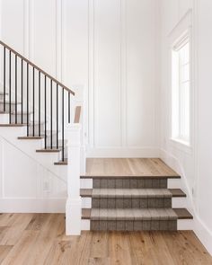 an empty room with white walls and wood floors, stairs leading up to the second floor