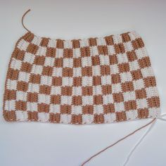 a brown and white crocheted blanket sitting on top of a table next to a string