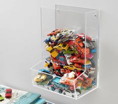 a clear acrylic container filled with assorted toy cars