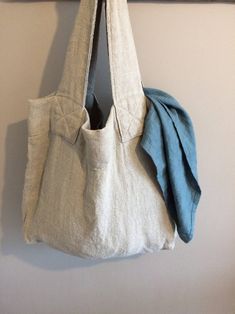 a white bag hanging on a wall next to a coat rack with a blue towel