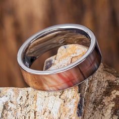 the wedding ring is sitting on top of a piece of wood, which has been polished and polished