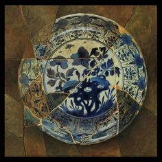 a blue and white plate sitting on top of a stone floor with an artistic design