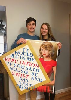 two people standing next to each other holding up a sign with words written on it