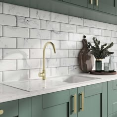 a kitchen with green cabinets and white marble counter tops, gold faucets and brass handles