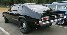 an old black muscle car parked in a parking lot