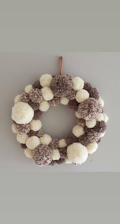 a white and brown wreath with pom - poms hanging from the front door