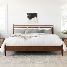 a bed with white sheets and pillows in a bedroom