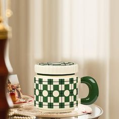 a green and white coffee mug sitting on top of a table next to other items