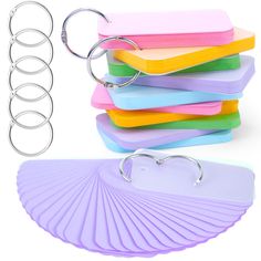 a stack of assorted colored paper with metal ring holders and clips to hold them