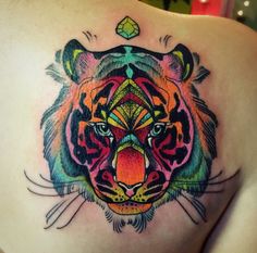 a colorful tiger tattoo on the back of a woman's left shoulder and chest