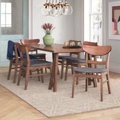 a dining room table with chairs and a vase on the rug in front of it