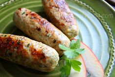 two sausages on a green plate with an apple and parsley garnish