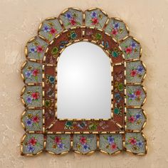 a decorative mirror with flowers on it is hanging on the wall next to a stucco wall