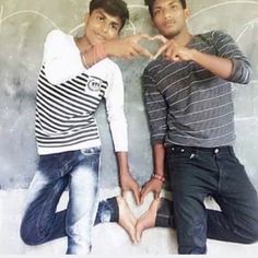 two young men standing next to each other with their hands in the shape of a heart