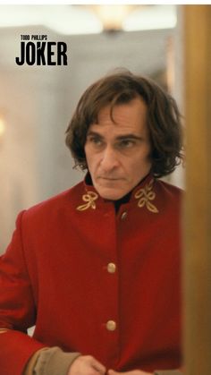 a man in a red jacket looking at the camera with an evil look on his face